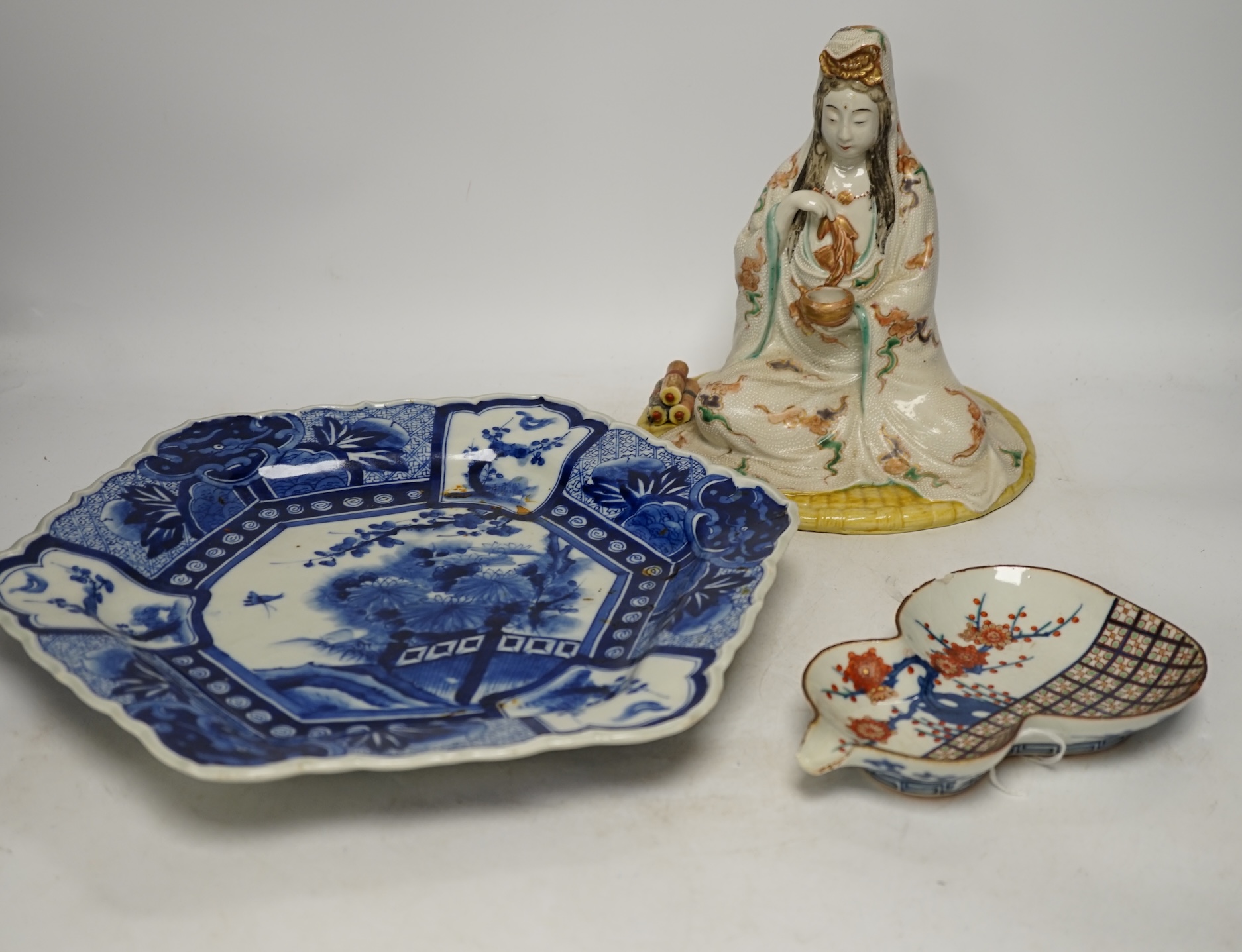 A Japanese seated porcelain figure of Kwannon, an Imari dish and a kakiemon style dish, largest 35cm diameter (3). Condition - blue dish good, others poor to fair